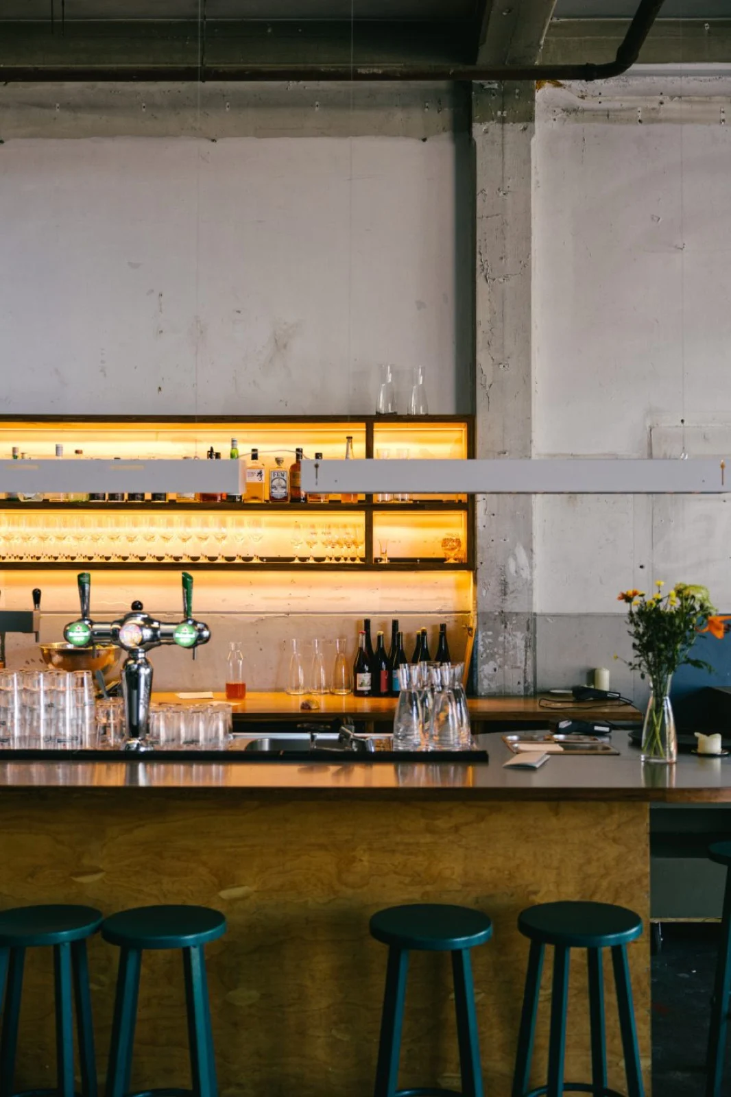 De bar van Bar Biloba met barkrukken en een verlichte flessenwand